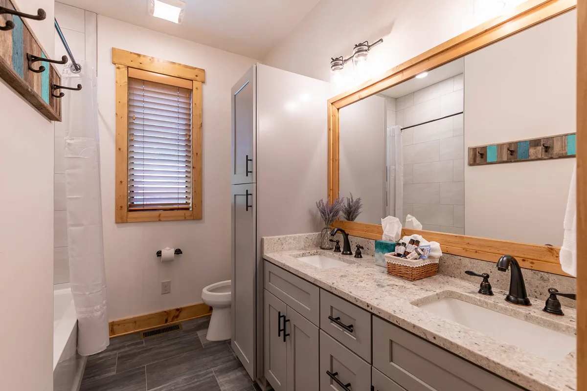 A modern bathroom featuring a vanity with double sinks, a large mirror, and elegant wooden accents. The room exudes tranquility and is well-suited for morning routines or winding down in the evening.
